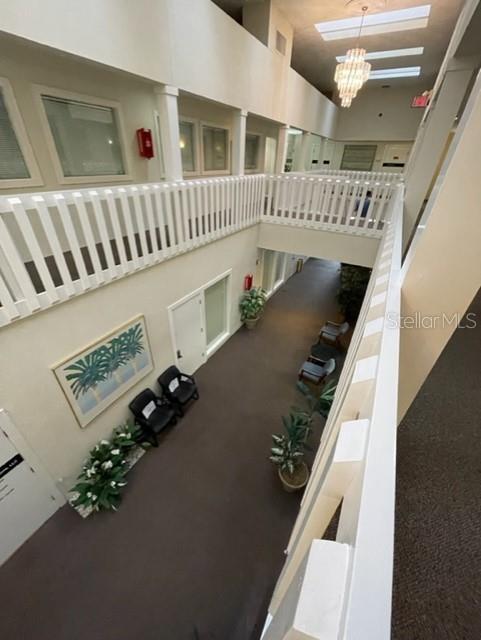 An elevated view of an indoor building hallway with white railings, carpeted floors, and seating areas — 901 DOUGLAS AVENUE UNIT 239, ALTAMONTE SPRINGS, FL