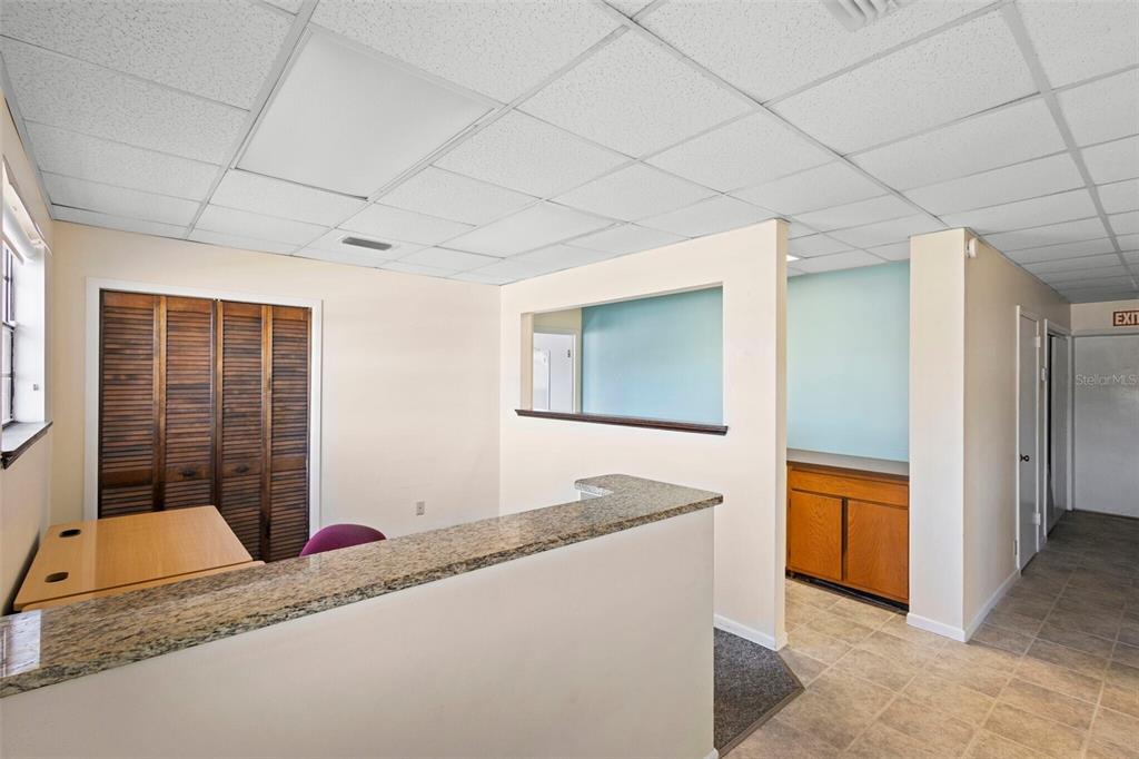 An office reception area features a granite-topped counter, drop ceiling, and wood-paneled closet doors — 1995 N VOLUSIA AVENUE, ORANGE CITY, FL