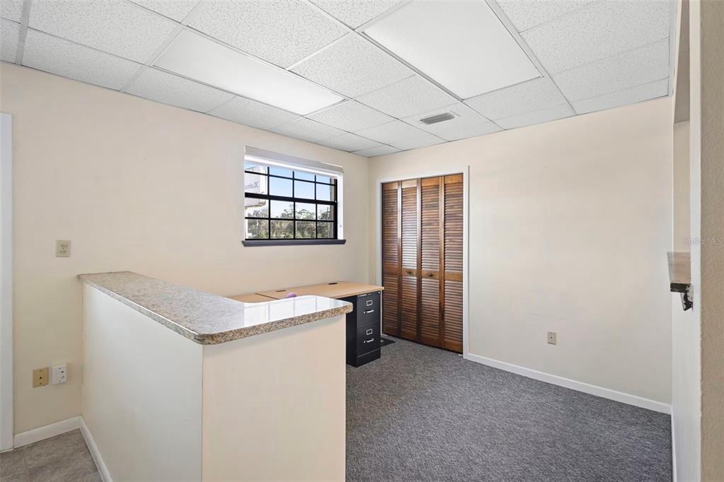 An office space features a granite-topped counter, a desk, a window, and wooden closet doors — 1995 N VOLUSIA AVENUE, ORANGE CITY, FL
