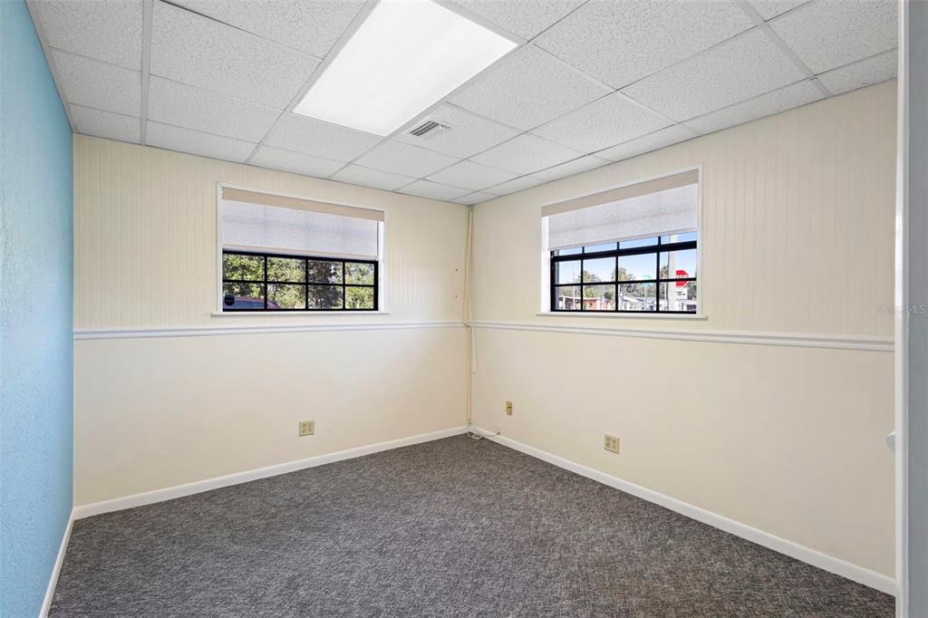 An empty office room features gray carpeting, beige walls with wainscoting, and a drop ceiling — 1995 N VOLUSIA AVENUE, ORANGE CITY, FL
