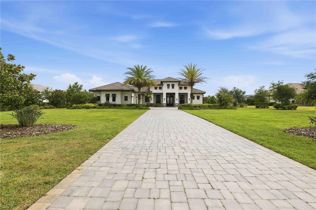 A paved driveway leads to the front entrance of a single-story house with palm trees — 8452 LINDRICK LANE, BRADENTON, FL