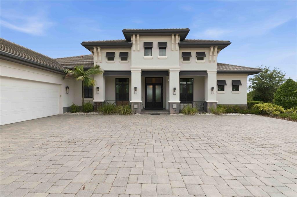 A modern two-story house with a paved driveway, white stucco exterior, and a dark roof — 8452 LINDRICK LANE, BRADENTON, FL