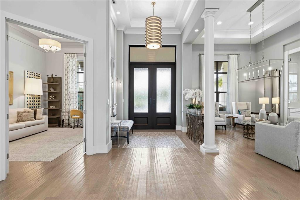 A bright foyer features light wood flooring, a central column, and double front doors — 8452 LINDRICK LANE, BRADENTON, FL