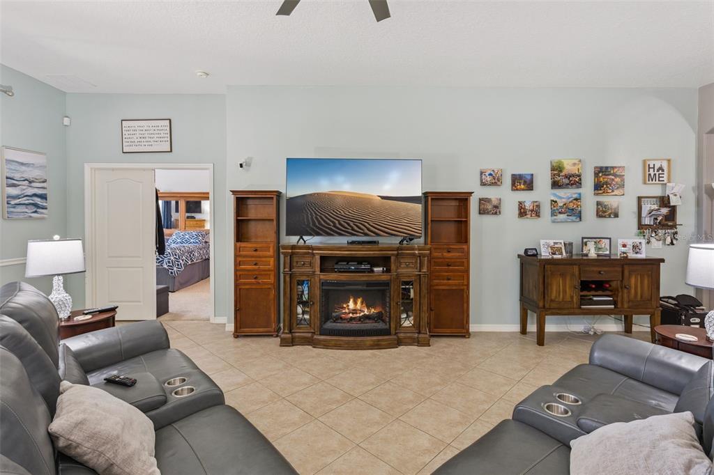 A living room features a fireplace media console, gray leather sofas, and light-colored tile flooring — 220 BAYOU BEND ROAD, GROVELAND, FL
