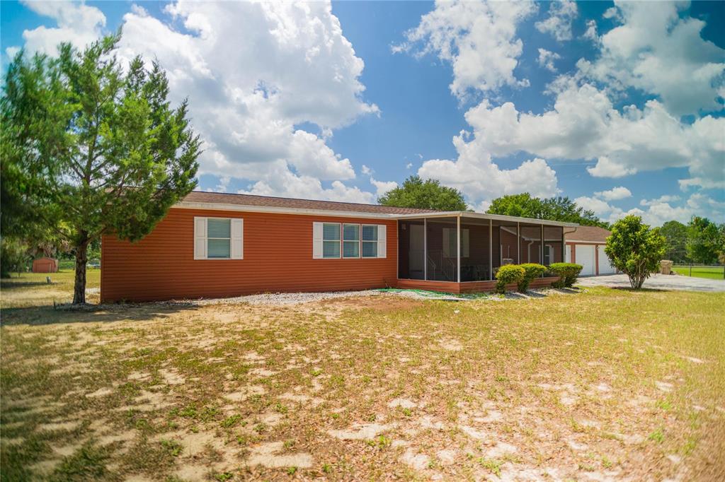 A single-story orange house with a screened-in porch and a detached garage — 4100 MARION COUNTY ROAD, WEIRSDALE, FL