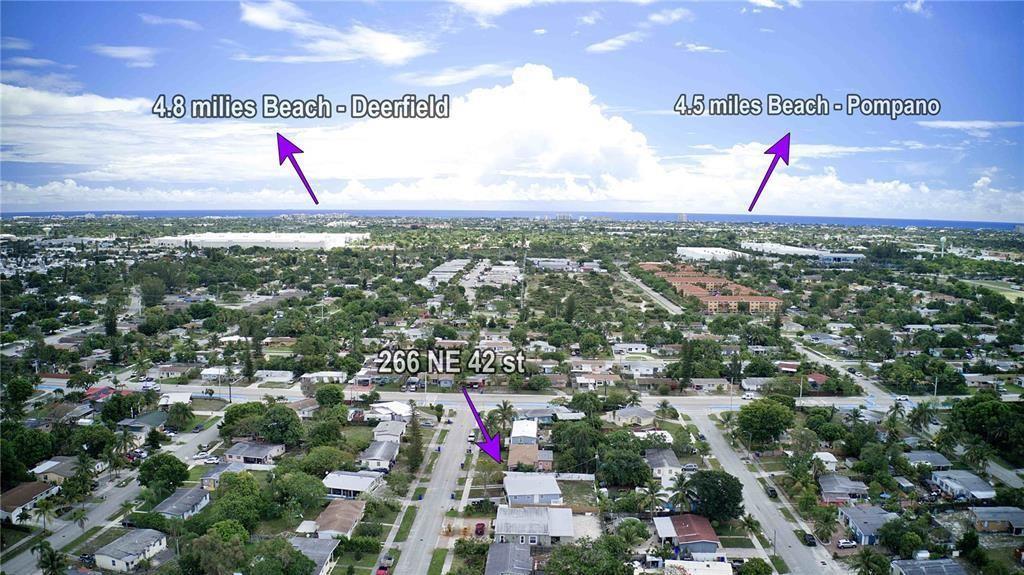 An aerial view shows a residential neighborhood with arrows pointing toward distant beach locations — 266 NE 42nd Street, Deerfield Beach FL 33064, DEERFIELD BEACH, FL