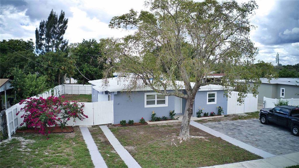 A single-story gray house with a white fence, a paved driveway, and a large tree — 266 NE 42nd Street, Deerfield Beach FL 33064, DEERFIELD BEACH, FL