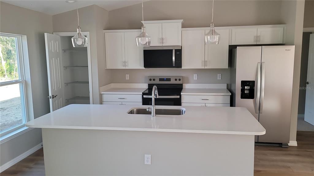 A kitchen features white cabinets, stainless steel appliances, a center island, and a walk-in pantry — 5982 N MATHESON DRIVE, CITRUS SPRINGS, FL
