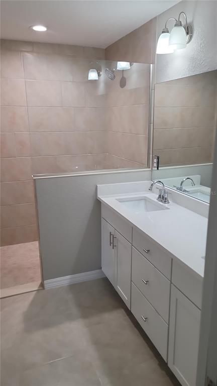 A bathroom features a white vanity with a sink, a mirror, and a tiled shower — 5982 N MATHESON DRIVE, CITRUS SPRINGS, FL