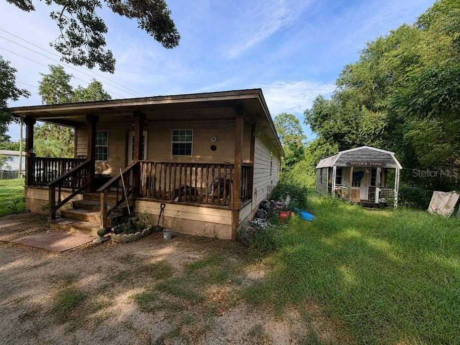 A single-story house with a front porch stands next to a small shed labeled Snyder Farm — 16142 SE 49TH STREET ROAD, OCKLAWAHA, FL