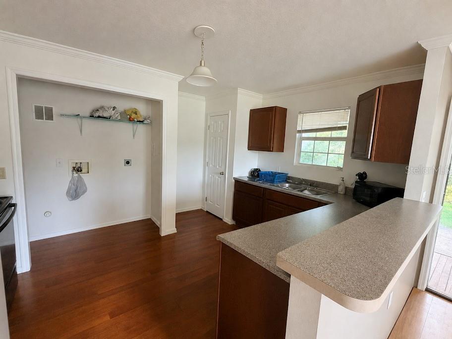 A kitchen features dark wood cabinets, a laminate countertop, and an adjacent laundry area — 16142 SE 49TH STREET ROAD, OCKLAWAHA, FL
