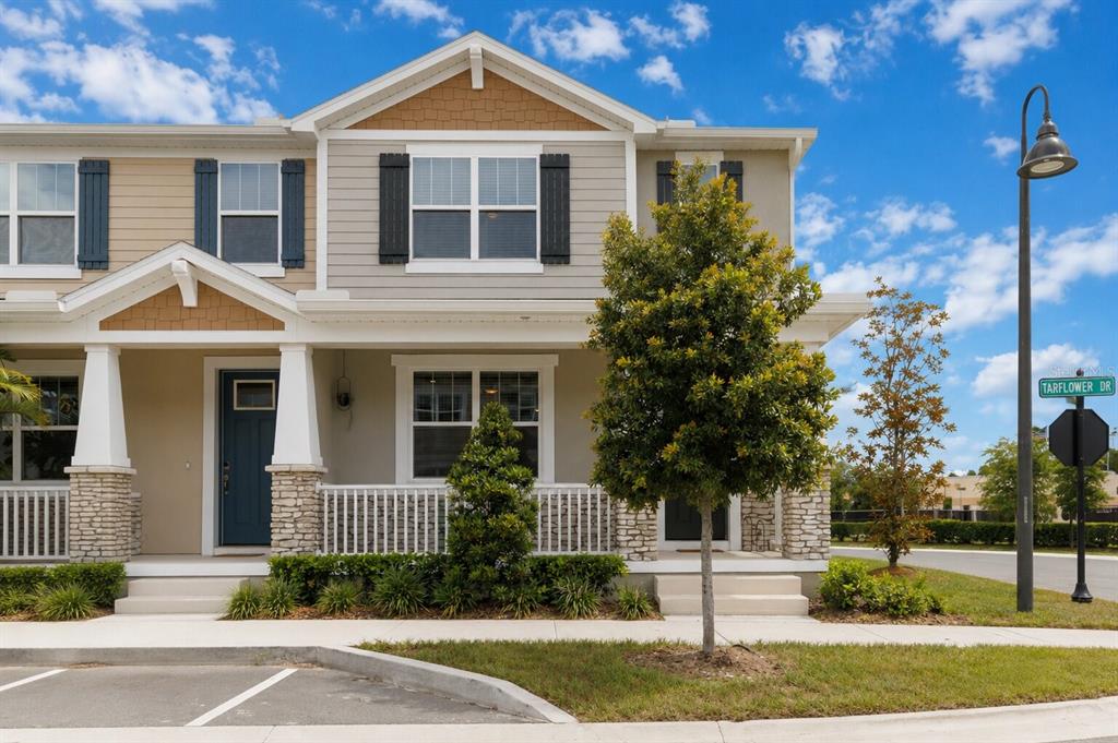 A two-story townhouse exterior features a front porch, stone accents, and a street sign — 1326 TARFLOWER DRIVE, WINTER SPRINGS, FL