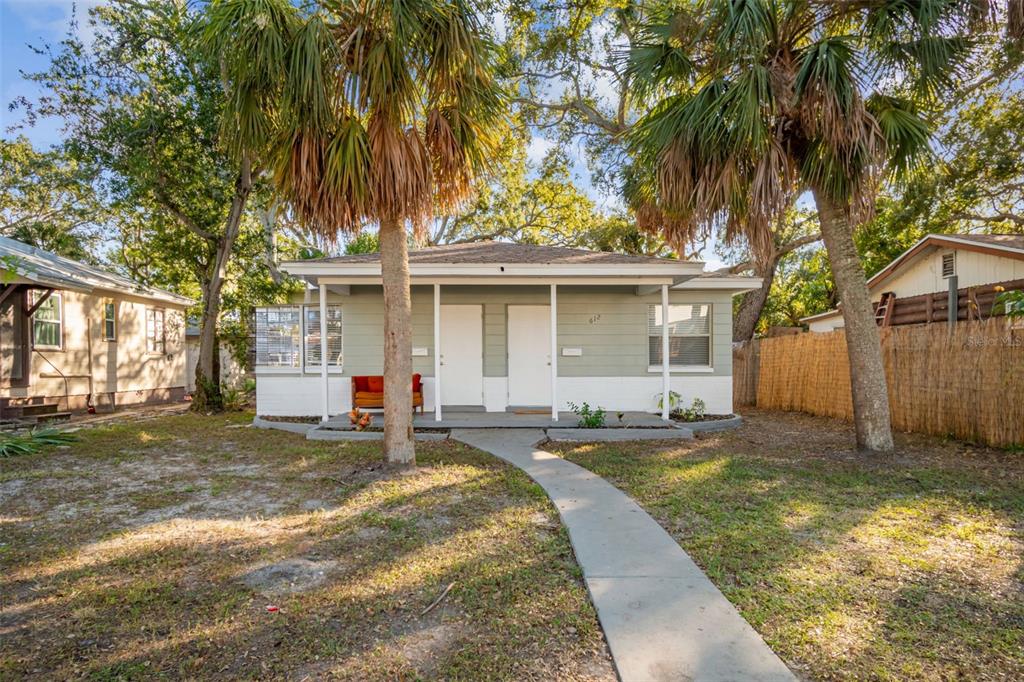 A single-story duplex with a covered front porch, two white doors, and palm trees — 610 16TH AVENUE S, ST PETERSBURG, FL