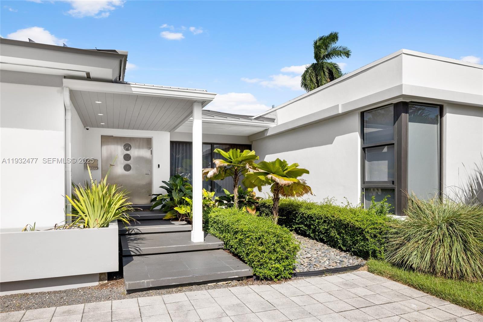The exterior of a modern house features a covered entryway with steps and landscaping — 6420 Pinetree Drive Cir, Miami Beach FL 33141, MIAMI BEACH, FL