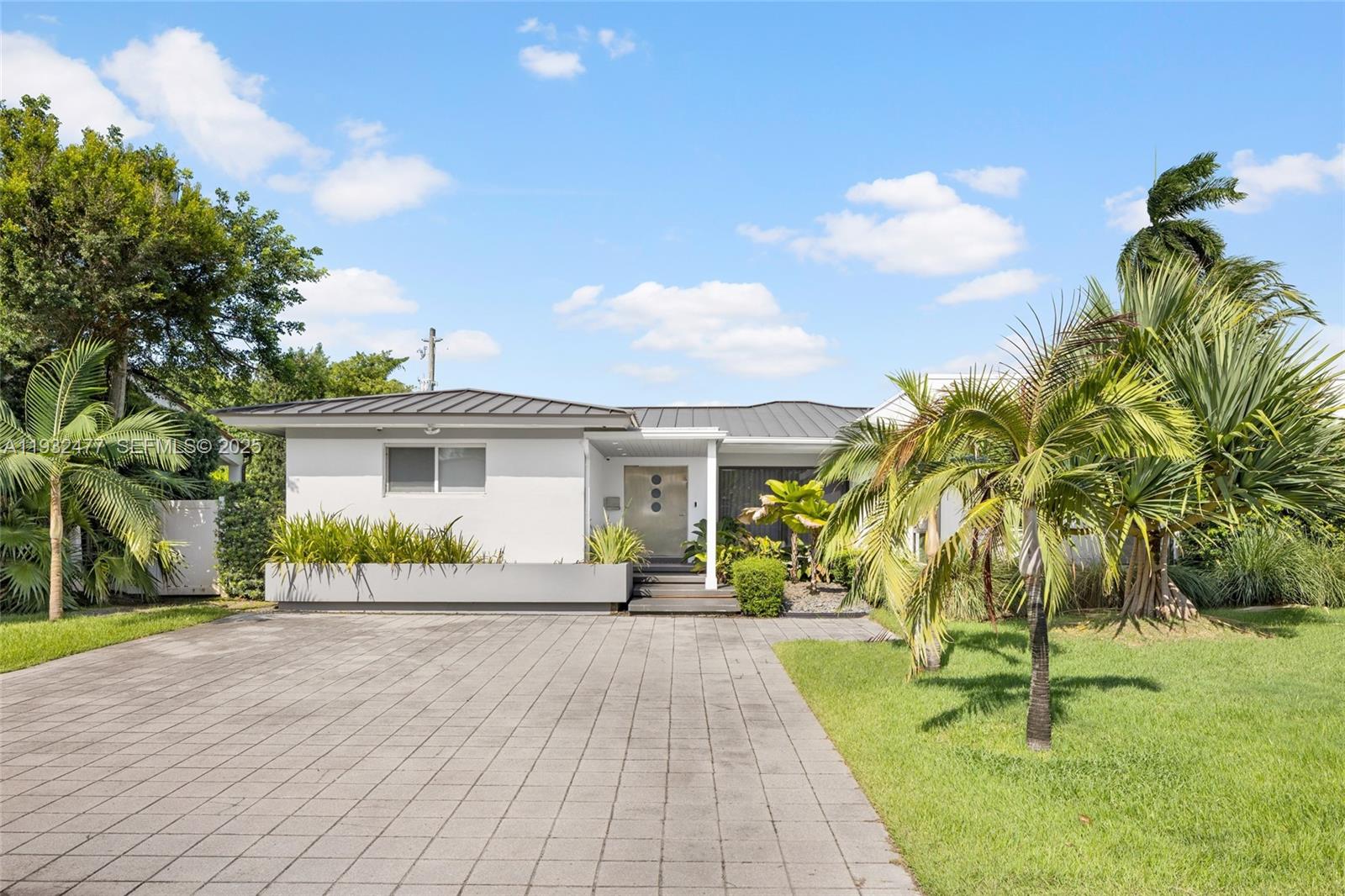 A single-story house with a metal roof, paved driveway, and palm trees in the yard — 6420 Pinetree Drive Cir, Miami Beach FL 33141, MIAMI BEACH, FL
