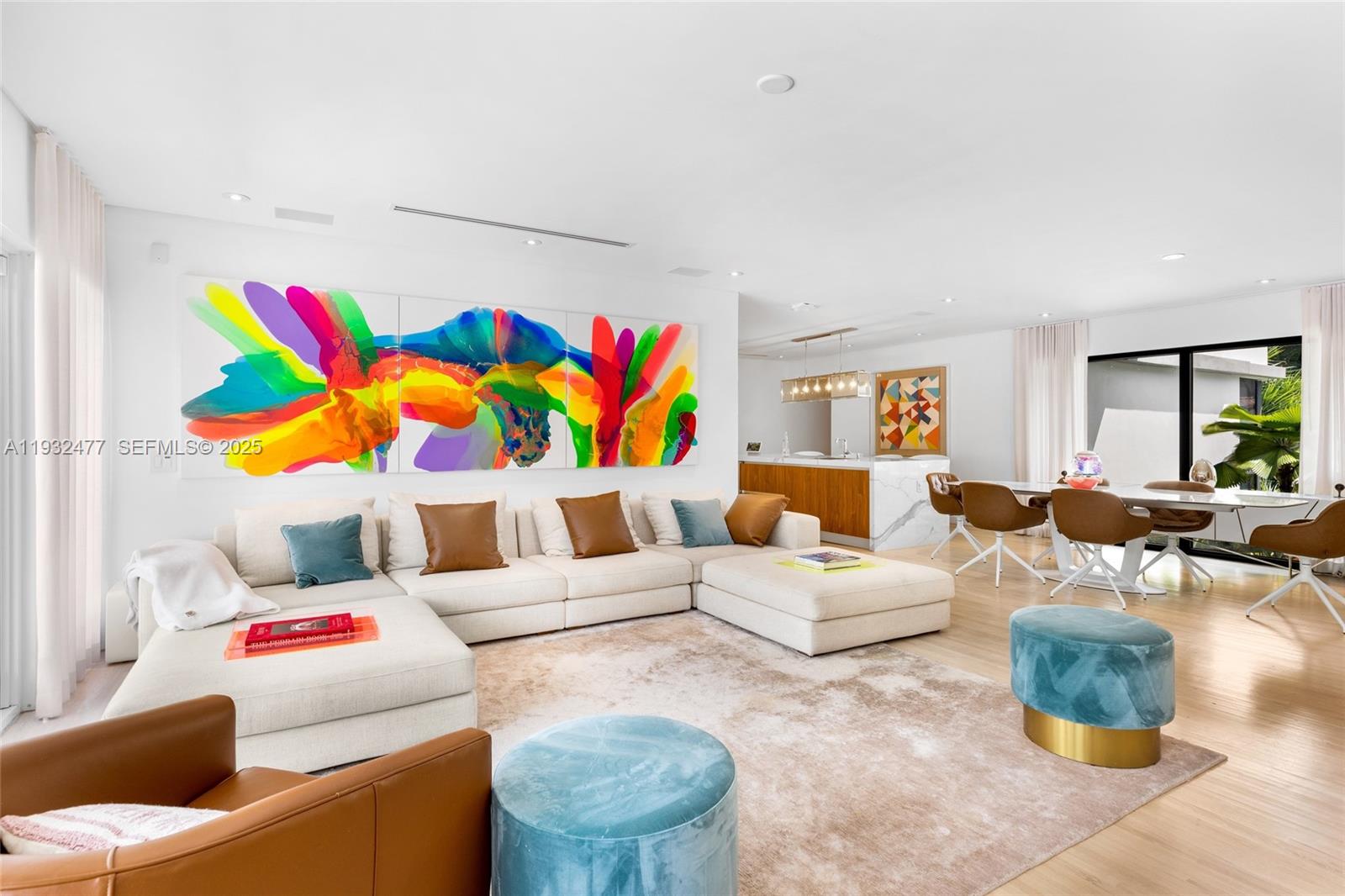A bright living room features a large sectional sofa, colorful wall art, and a dining area — 6420 Pinetree Drive Cir, Miami Beach FL 33141, MIAMI BEACH, FL