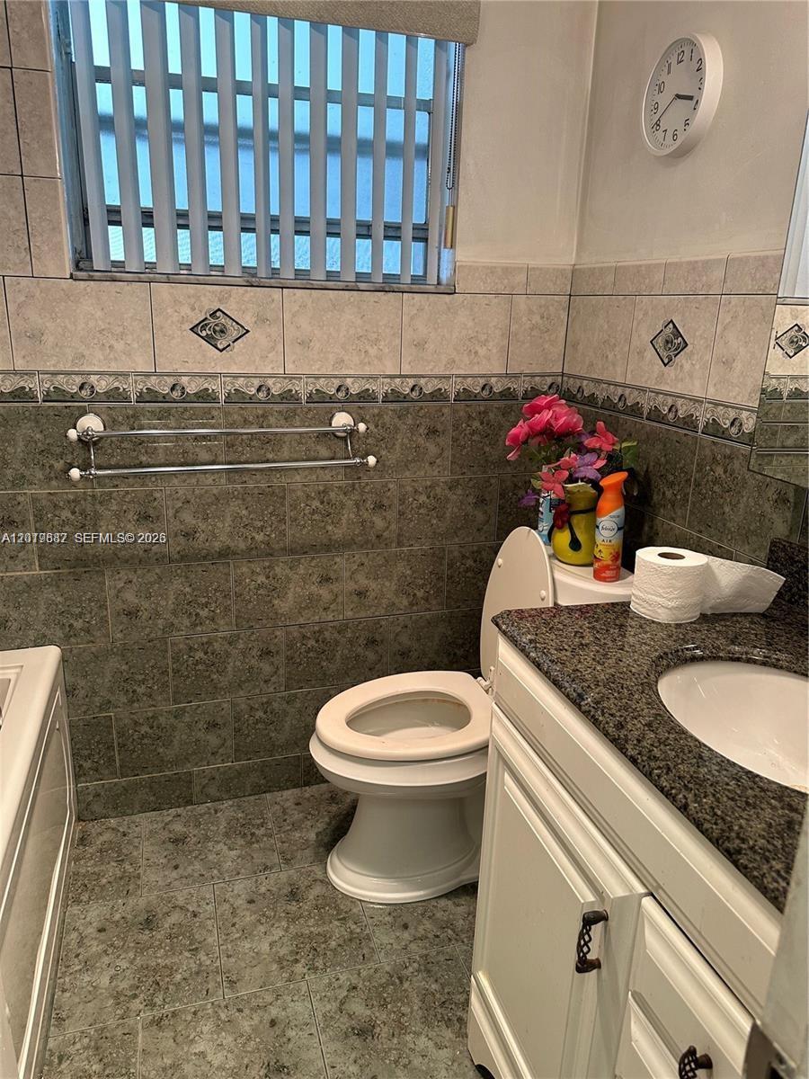 A bathroom features a toilet, a vanity with a granite countertop, and tiled walls — 19051 NE 2nd Ave # 1514, Miami FL 33179, MIAMI, FL