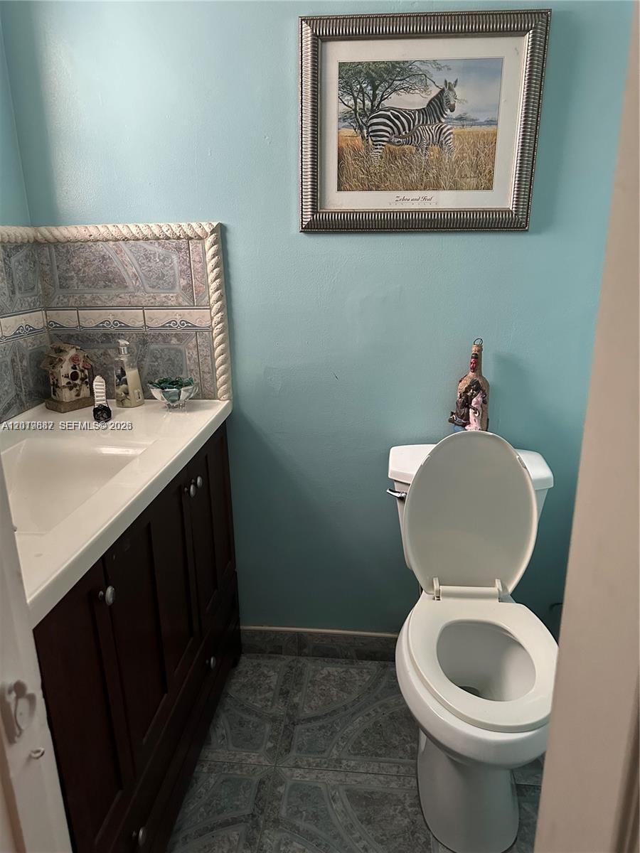 A small bathroom features a vanity with a tiled backsplash, a toilet, and zebra-themed wall art — 19051 NE 2nd Ave # 1514, Miami FL 33179, MIAMI, FL