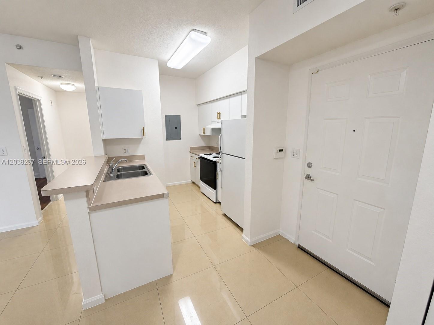 A kitchen features white cabinets, a white refrigerator, a black stove, and beige tile flooring — 7000 SW 80th St # 401, Miami FL 33143, MIAMI, FL