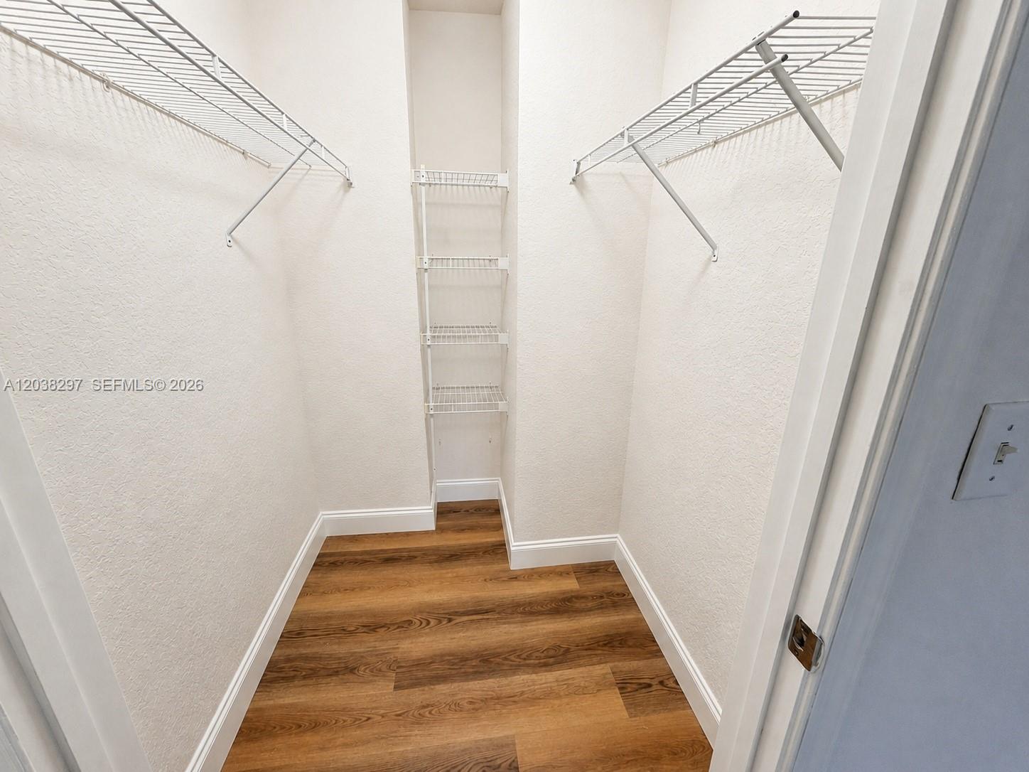 A walk-in closet features wire shelving, white walls, and wood-look flooring — 7000 SW 80th St # 401, Miami FL 33143, MIAMI, FL