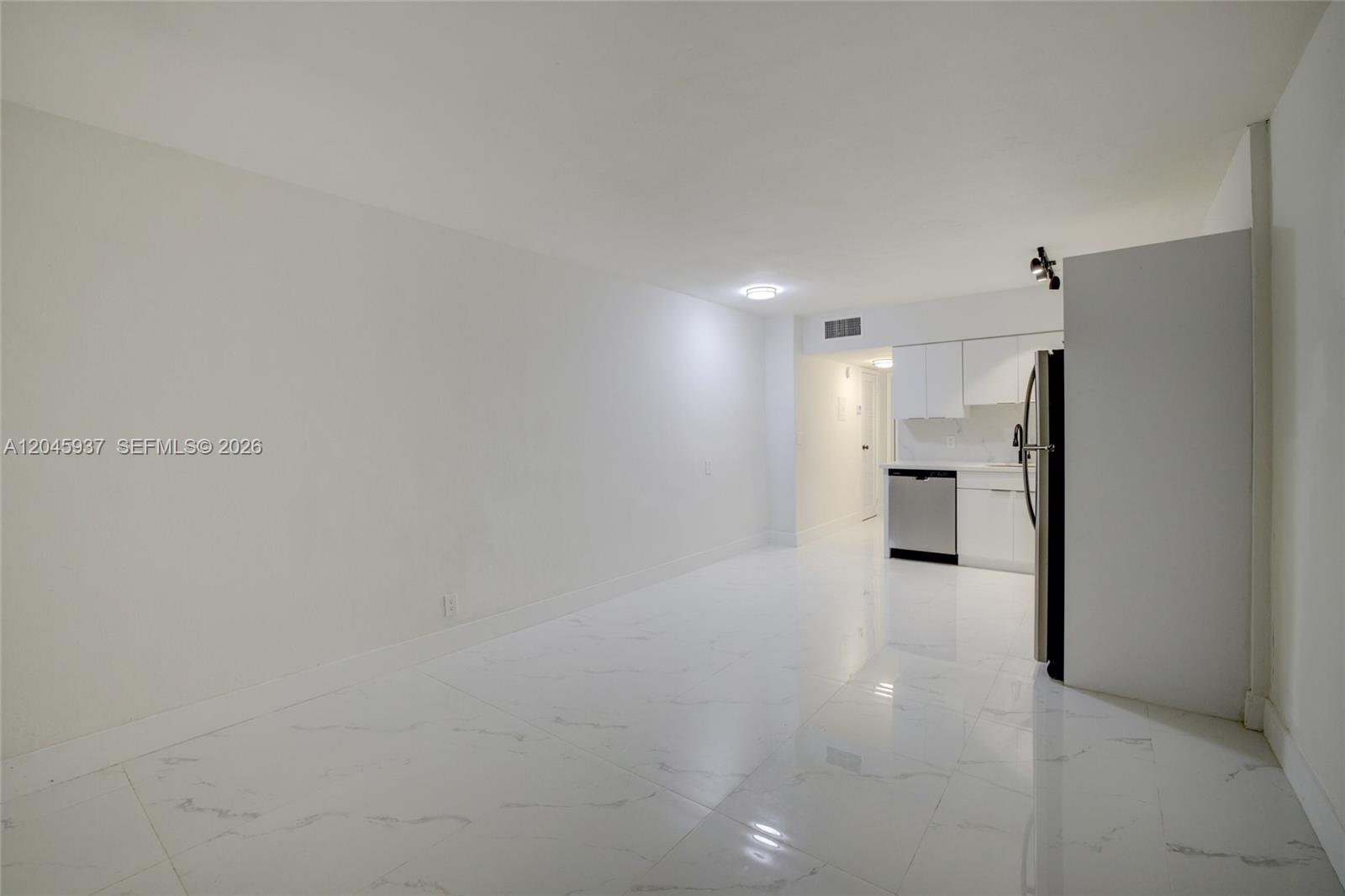 An open-concept living area features white walls, marble-patterned tile floors, and a small kitchen — 1740 Funston ST # 6, Hollywood FL 33020, HOLLYWOOD, FL