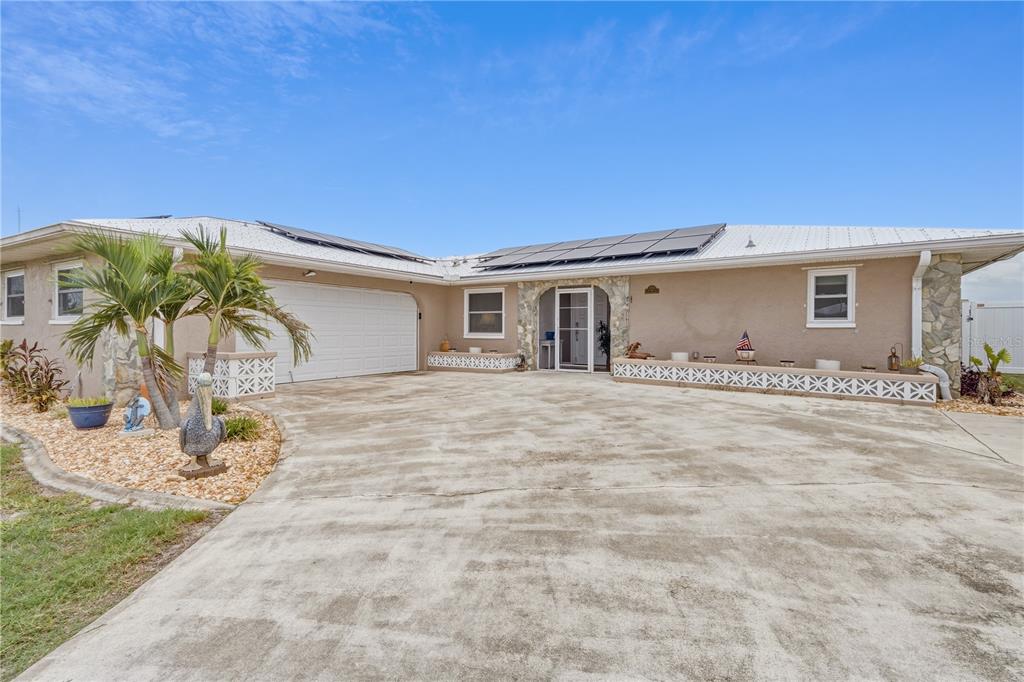 A single-story house with a concrete driveway, solar panels, and a stone-accented entryway — 2284 BROAD RANCH DRIVE, PORT CHARLOTTE, FL