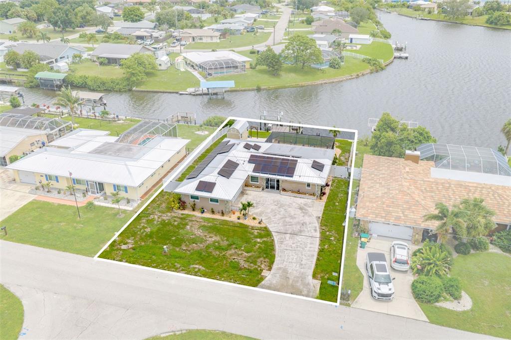 An aerial view of a waterfront house with solar panels and a concrete driveway — 2284 BROAD RANCH DRIVE, PORT CHARLOTTE, FL
