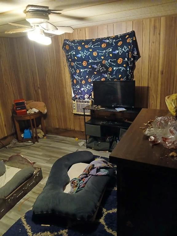 A room with wood-paneled walls features a ceiling fan, a television, and a floor cushion — 14847 SE 47TH COURT, SUMMERFIELD, FL