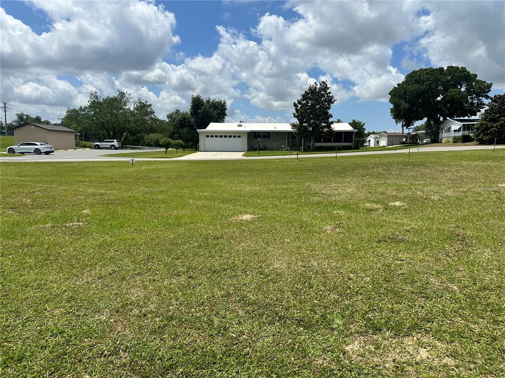 A large, grassy vacant lot sits in the foreground with a house visible behind it — 3951 GREENBLUFF ROAD UNIT 816, ZELLWOOD, FL