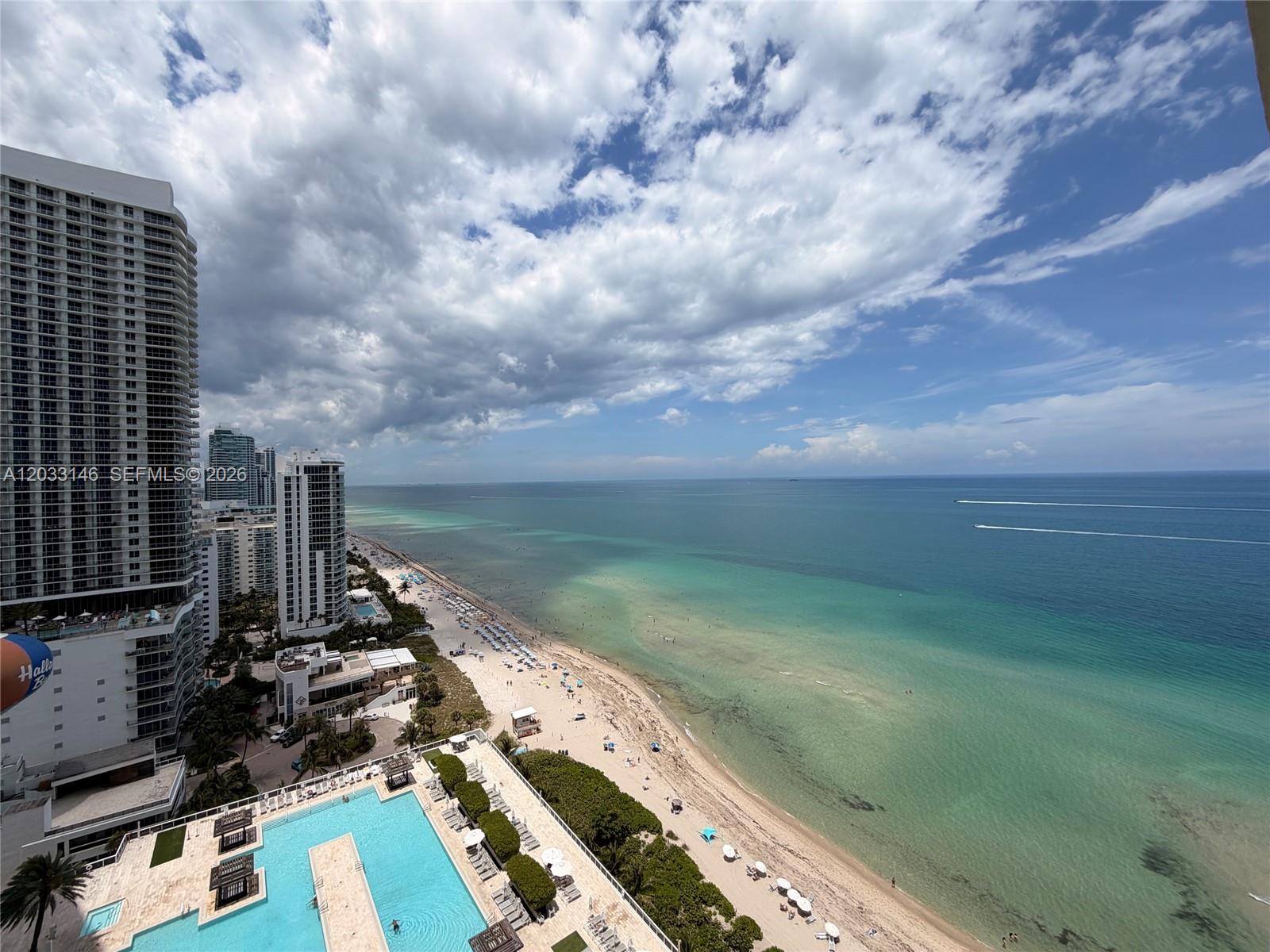 An elevated view shows a swimming pool deck overlooking a sandy beach and the ocean — 1830 S Ocean Dr # 2412, Hallandale Beach FL 33009, HALLANDALE BEACH, FL