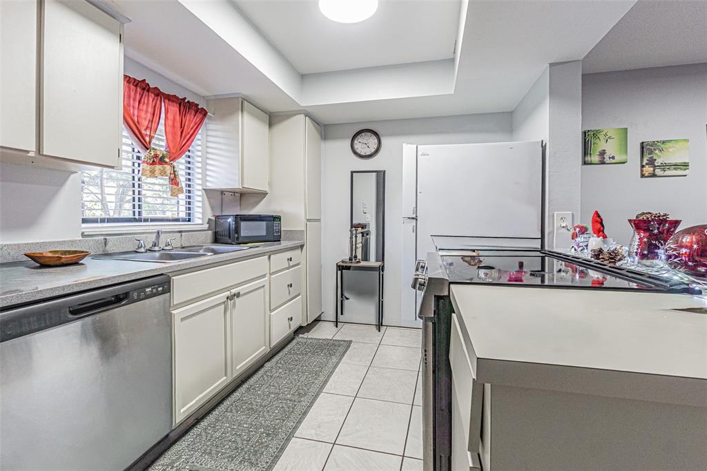 A kitchen features white cabinets, stainless steel appliances, a tiled floor, and a window — 4010 OAK LIMB COURT, TAMPA, FL