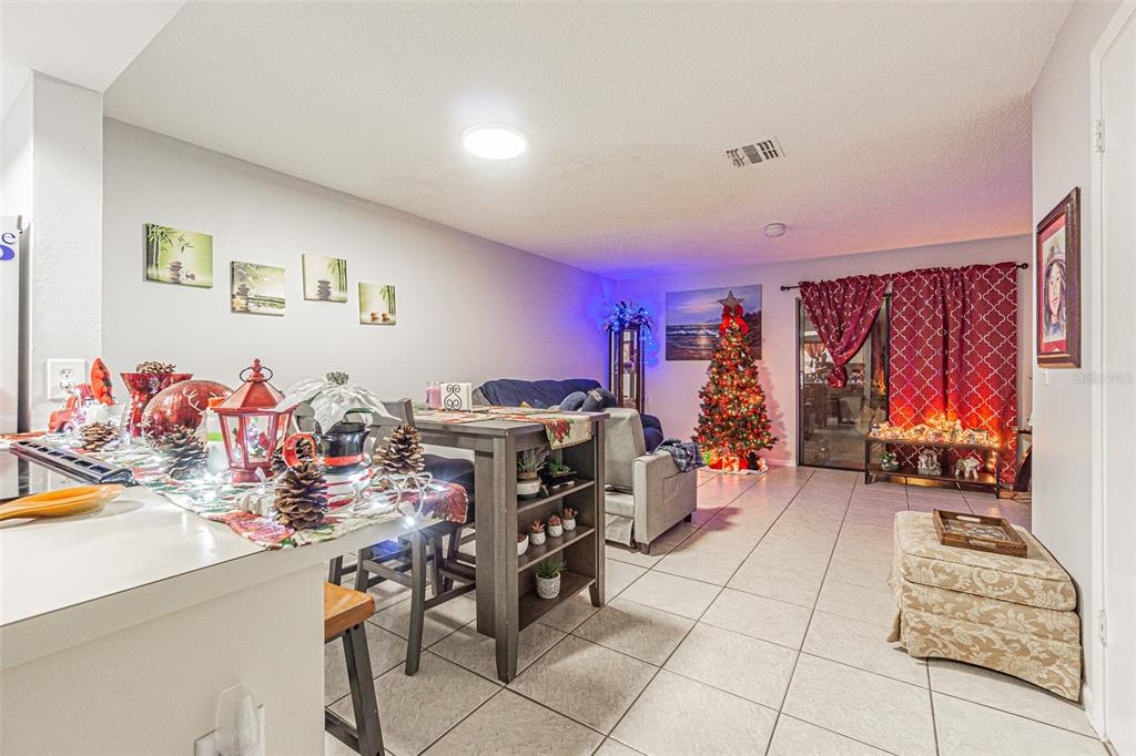 A living room and dining area with tile floors, a Christmas tree, and sliding glass doors — 4010 OAK LIMB COURT, TAMPA, FL