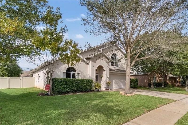 A single-story house with a beige stucco exterior, a front lawn, and a concrete driveway — 254 BRIDGE CREEK BOULEVARD, OCOEE, FL