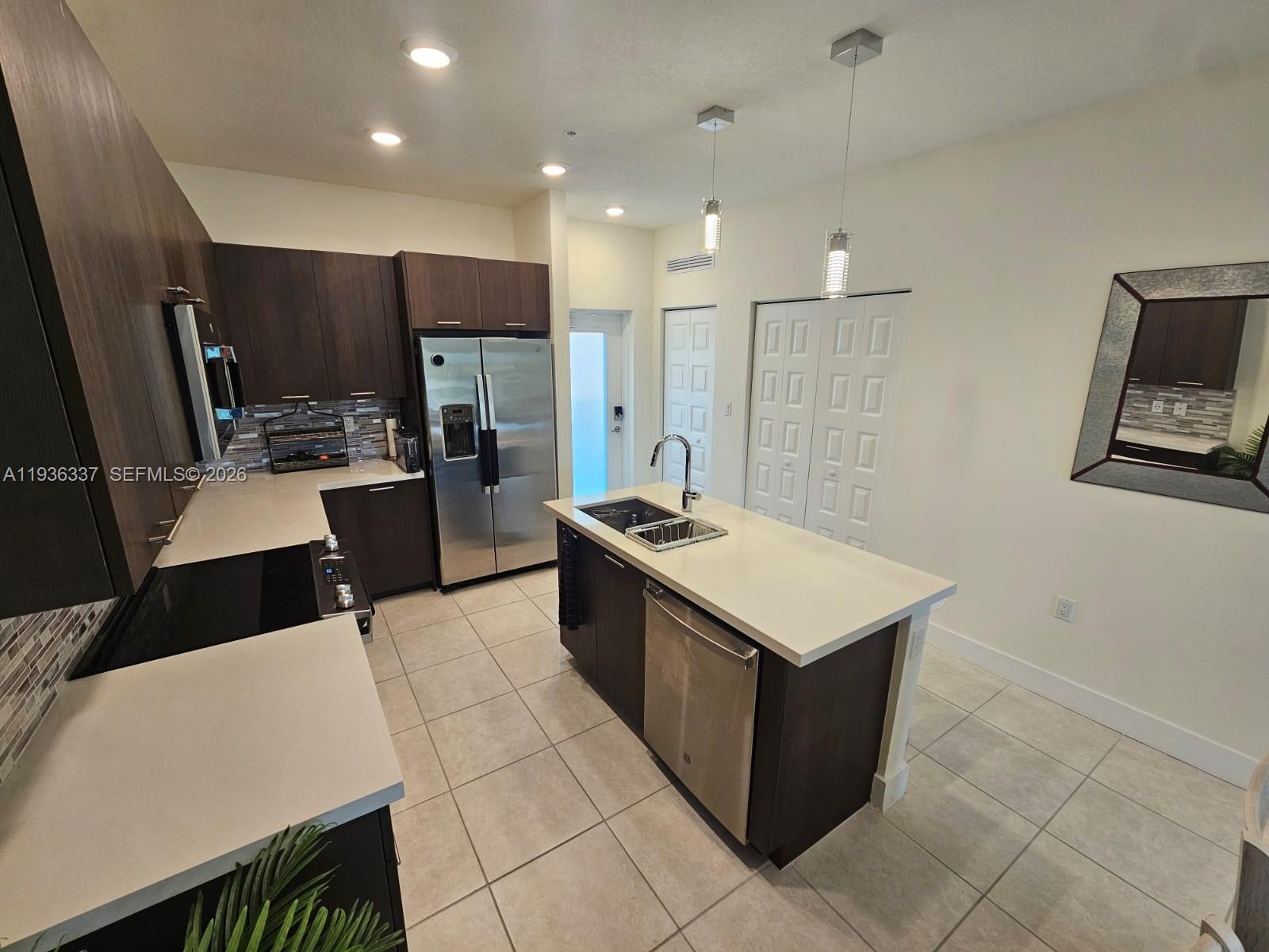A modern kitchen features dark wood cabinets, stainless steel appliances, and a central island — 8301 NW 41st St # 402, Doral FL 33166, DORAL, FL