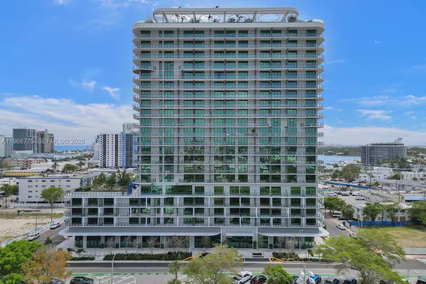 An exterior view of a modern high-rise residential building with glass balconies and a rooftop — 580 72nd St # 705, Miami Beach FL 33141, MIAMI BEACH, FL