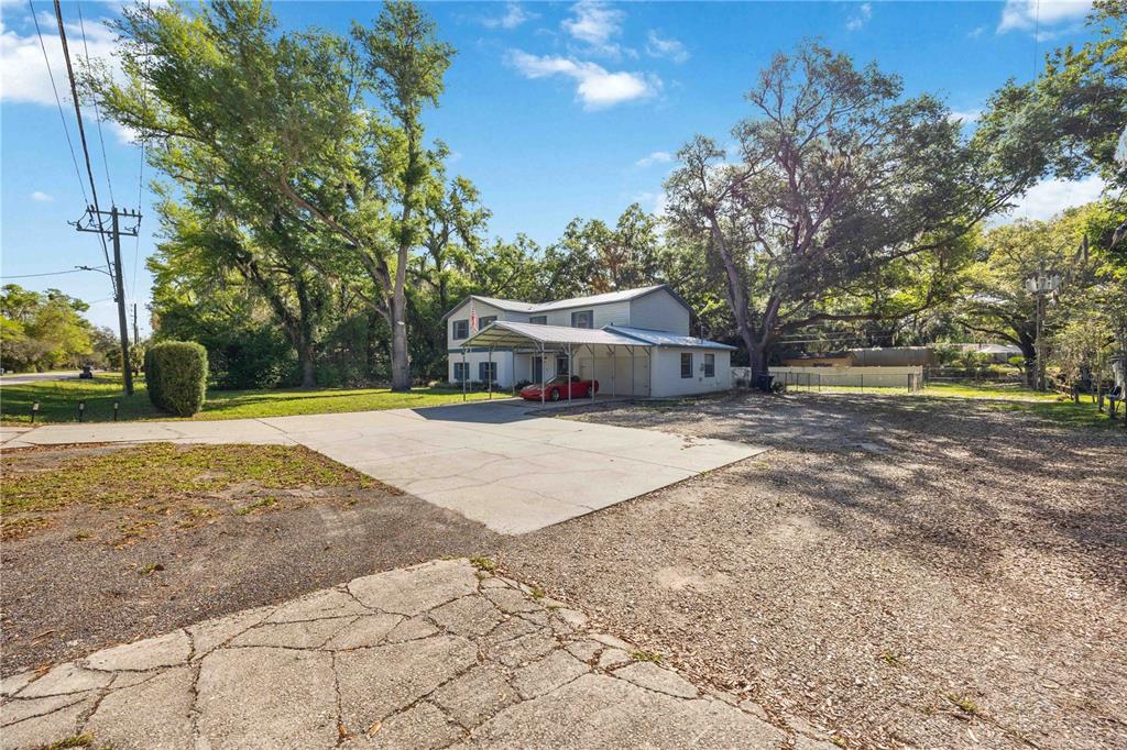 A two-story house with a metal carport sits on a large lot with gravel — 1035 OLD POLK CITY ROAD, LAKELAND, FL