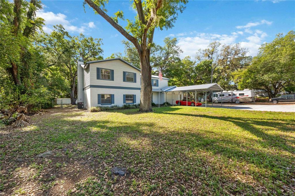 A two-story house with a metal carport, a red sports car, and an RV parked outside — 1035 OLD POLK CITY ROAD, LAKELAND, FL