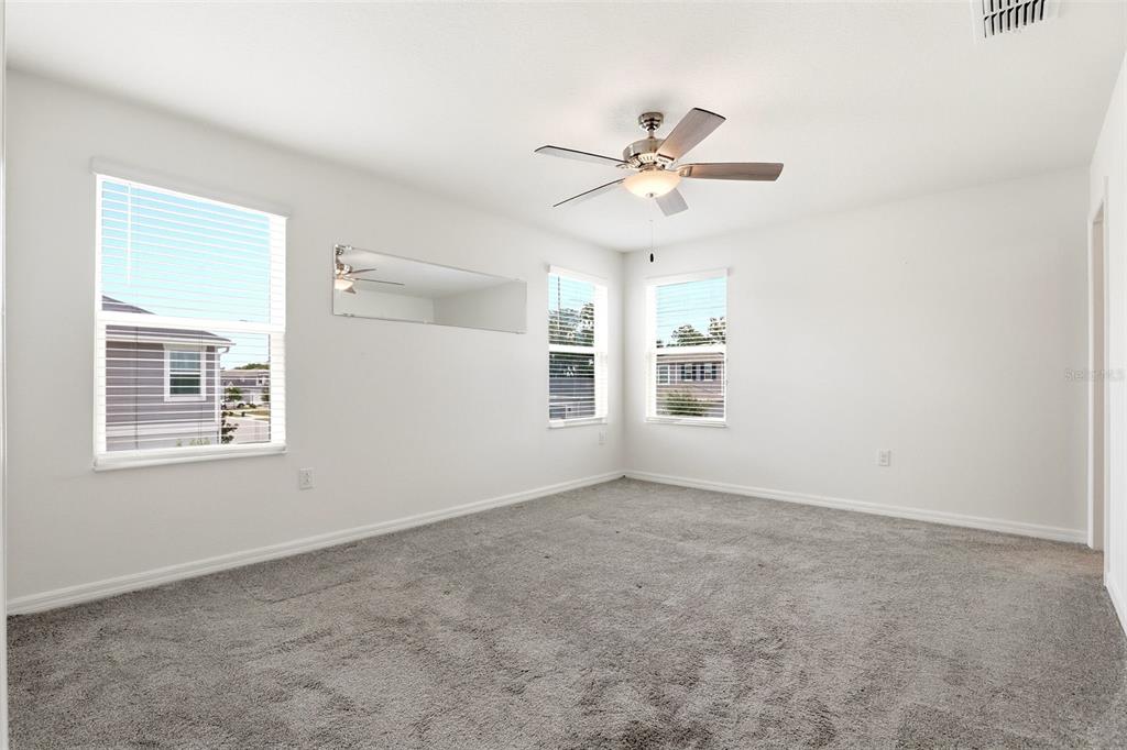 An empty bedroom features white walls, gray carpeting, a ceiling fan, and three windows — 2274 CARRABELLE WAY, SANFORD, FL