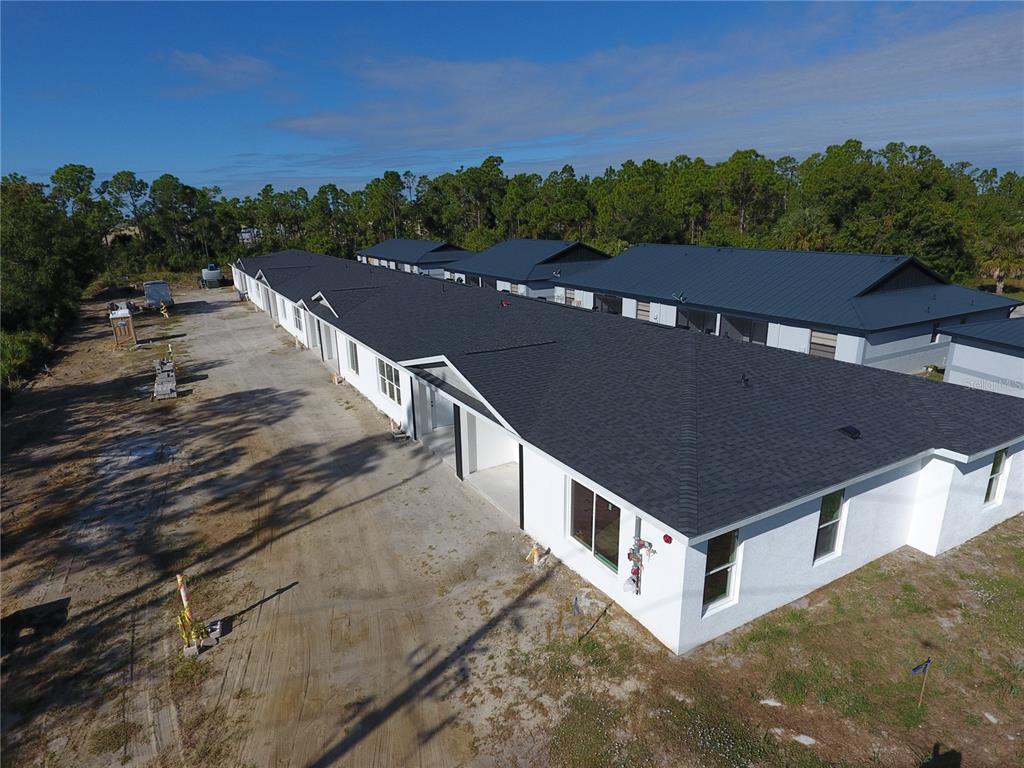 An aerial view of a newly constructed white multi-unit residential building with a dark roof — 1215 CAPRICORN BOULEVARD, PUNTA GORDA, FL