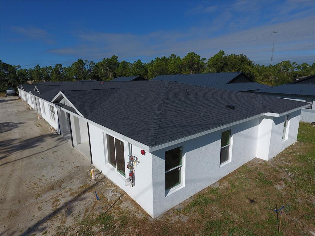 An aerial view of a newly constructed white stucco building with a dark shingled roof — 1215 CAPRICORN BOULEVARD, PUNTA GORDA, FL
