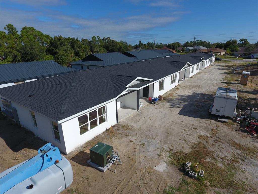 An aerial view of a newly constructed white residential building with a dark shingled roof — 1215 CAPRICORN BOULEVARD, PUNTA GORDA, FL