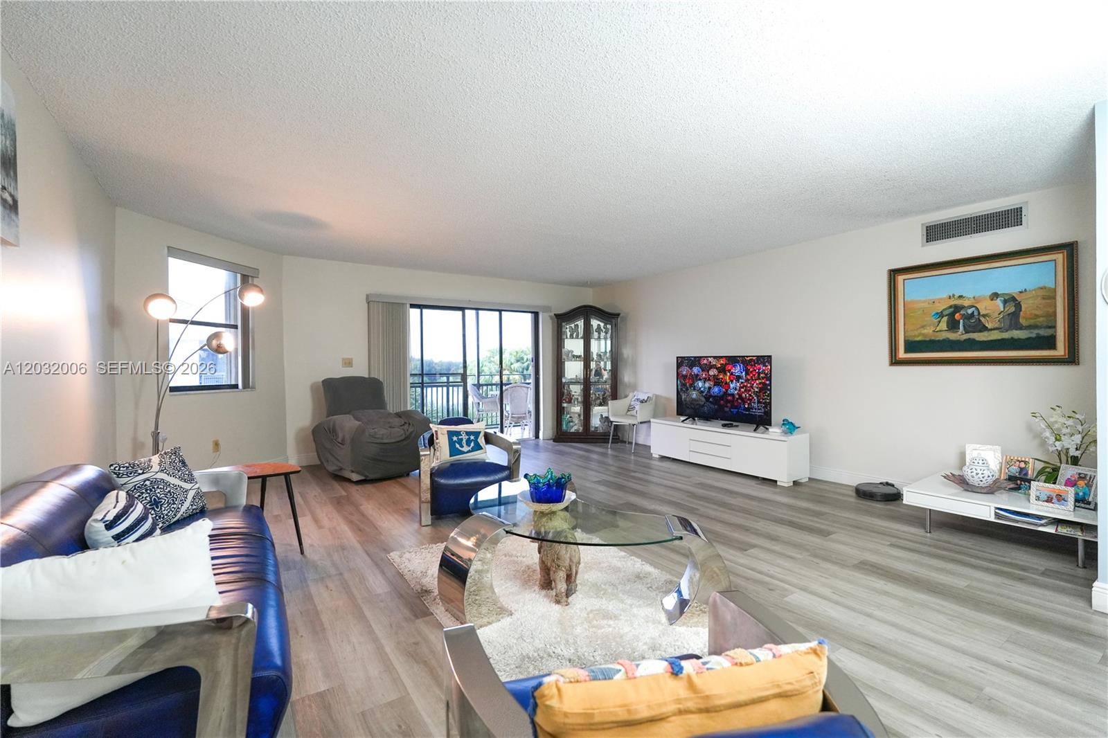 A living room features light wood-look flooring, a blue leather sofa, and a glass coffee table — 16051 Blatt Blvd # 401, Weston FL 33326, WESTON, FL