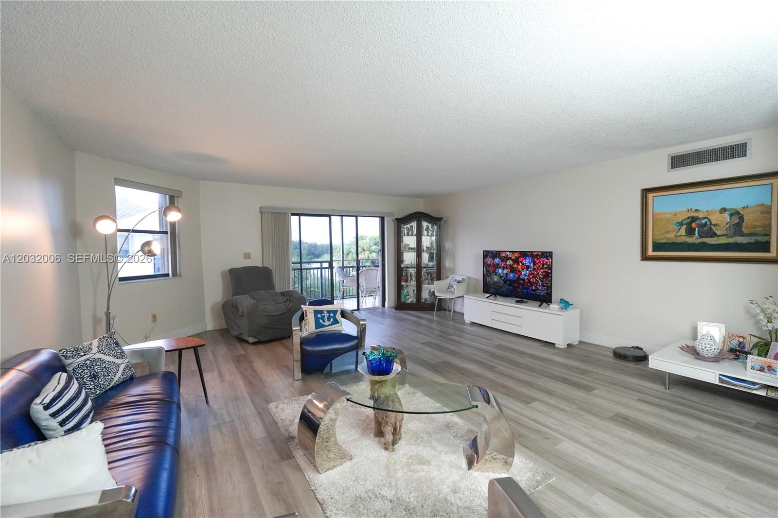 A living room features light wood-look flooring, a blue leather sofa, and a glass coffee table — 16051 Blatt Blvd # 401, Weston FL 33326, WESTON, FL