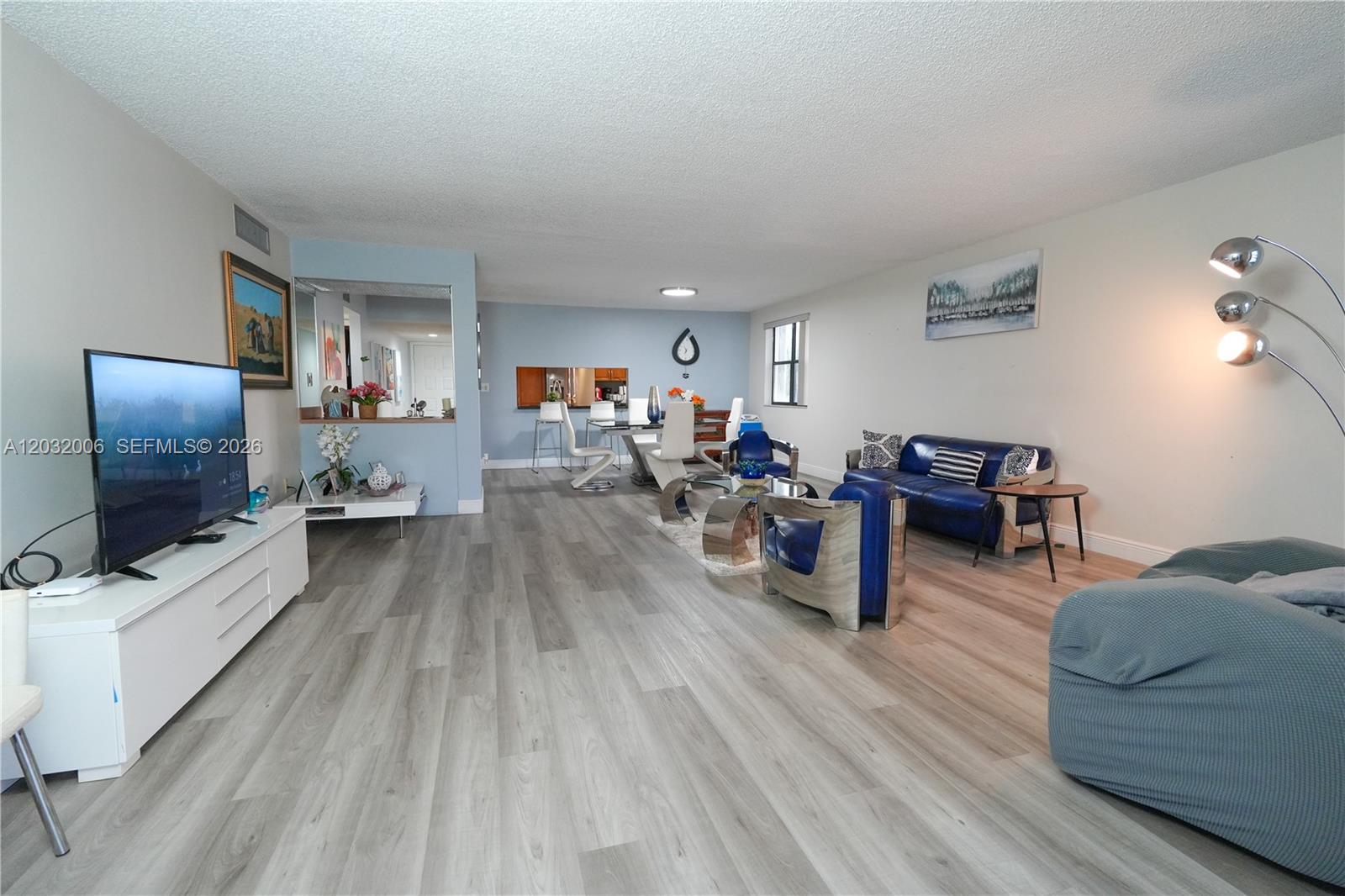 A living and dining area features light wood-look flooring, blue accent walls, and modern furniture — 16051 Blatt Blvd # 401, Weston FL 33326, WESTON, FL