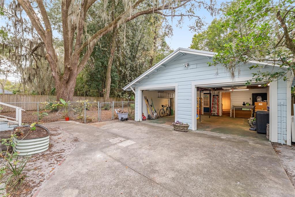 A detached two-car garage with light blue siding sits on a concrete driveway near trees — 929 NE 7TH AVENUE, GAINESVILLE, FL