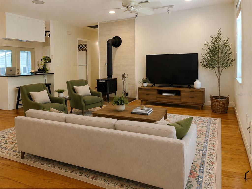 A living room features a wood-burning stove, a television on a console, and green armchairs — 929 NE 7TH AVENUE, GAINESVILLE, FL