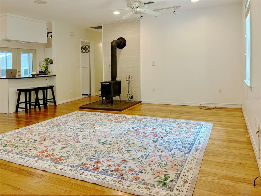 A living room features hardwood floors, a wood-burning stove, and a floral area rug — 929 NE 7TH AVENUE, GAINESVILLE, FL