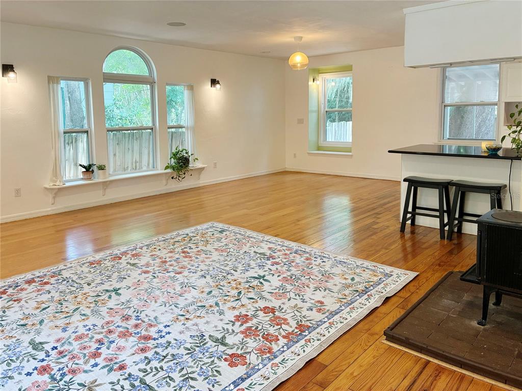 A living area with hardwood floors, a floral rug, and a kitchen breakfast bar — 929 NE 7TH AVENUE, GAINESVILLE, FL