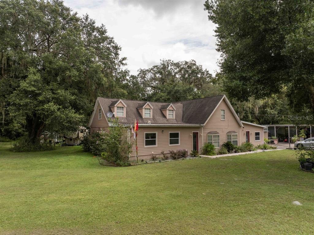 A tan, two-story house with a gabled roof and dormer windows sits on a grassy lot — 3500 N US HIGHWAY 301, WILDWOOD, FL