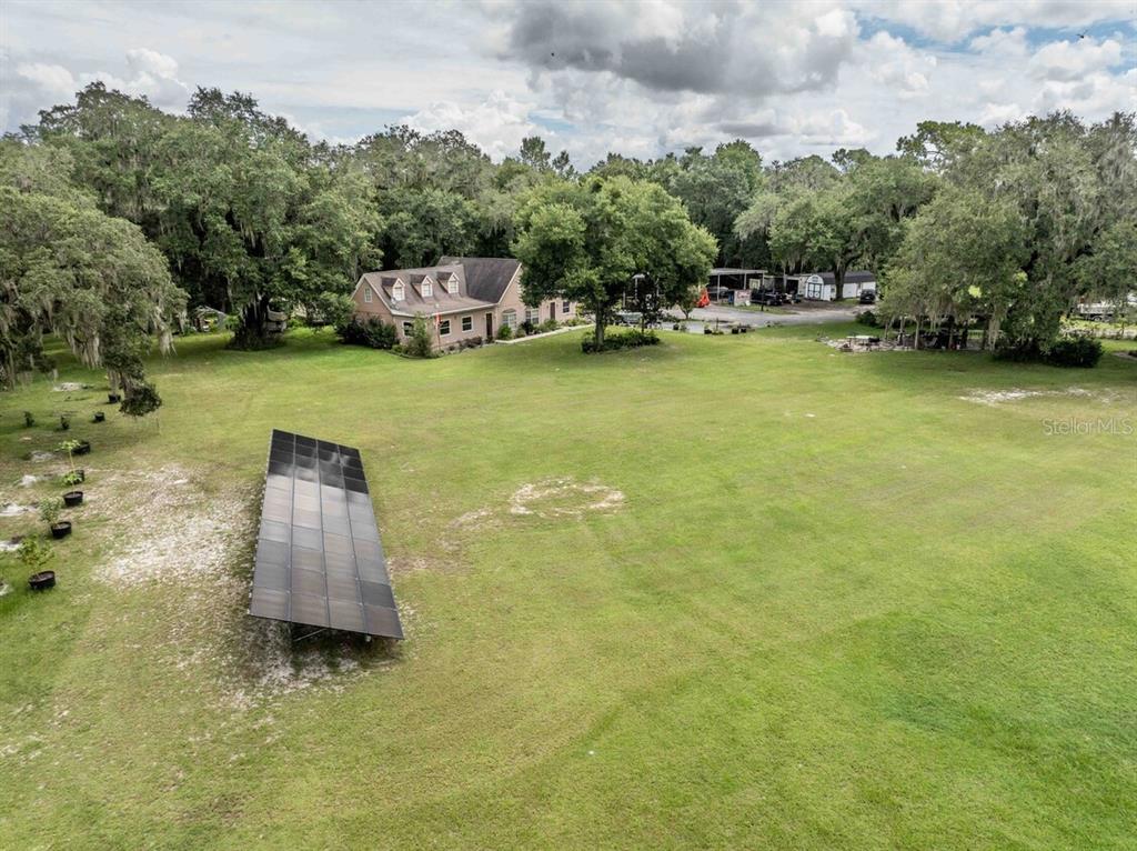 An aerial view shows a large grassy yard with a ground-mounted solar panel array — 3500 N US HIGHWAY 301, WILDWOOD, FL
